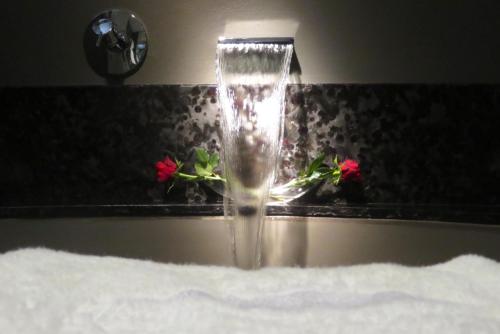 a water faucet on a bathroom counter with flowers at Atlanticview Cape Town Boutique Hotel in Cape Town