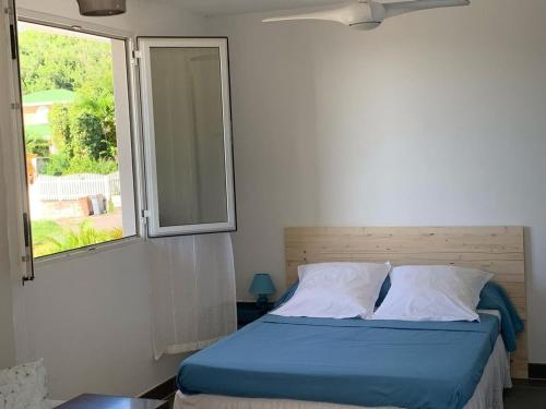 a bed in a room with a window at Bleu Cannelle et Petimo in Le Diamant