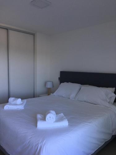 Una cama blanca con dos toallas encima. en DOS ORILLAS 413 BY GM RENTALS, en Colonia del Sacramento
