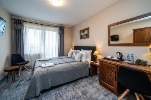 a bedroom with a bed and a desk and a mirror at Pensjonat Orlik Mountain Resort&SPA in Bukowina Tatrzańska