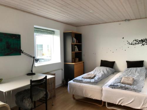 1 Schlafzimmer mit 2 Betten und einem Schreibtisch mit einer Lampe in der Unterkunft Light & spacious home in Tórshavn