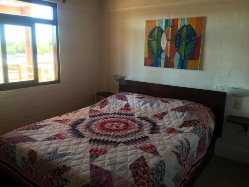 a bedroom with a quilt on a bed with a window at Casa Ananda Peru in Los Órganos