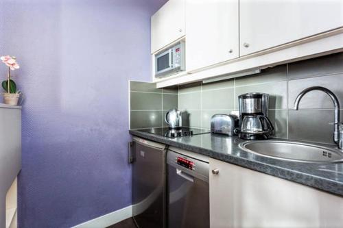 une cuisine avec un évier et un plan de travail dans l'établissement Appartement Lilas Parc 1 - Paris La Défense, à Courbevoie