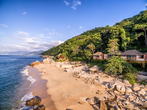 a beach in front of a house and the ocean at Xinalani Retreat Mexico in Qumiste
