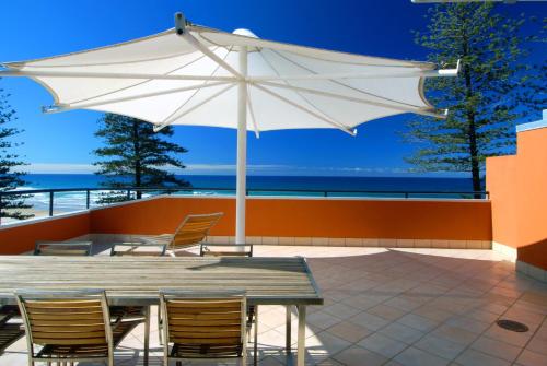 a patio with a table and chairs and an umbrella at The Beach Retreat Coolum in Coolum Beach