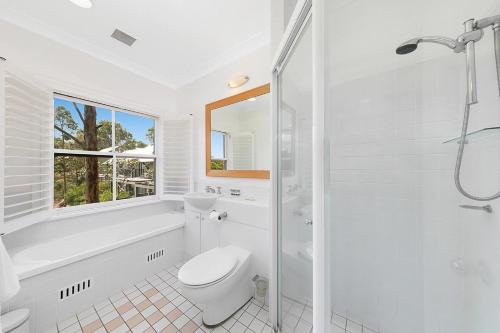 a white bathroom with a toilet and a shower at 2 Bedroom Villa @ Oaks Cypress Lakes Resort in Pokolbin