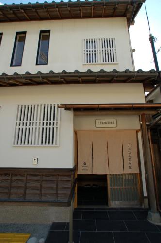 un edificio con una puerta abierta con un cartel. en 三上勘兵衛本店 Mikami Kanbe Honten en Miyazu