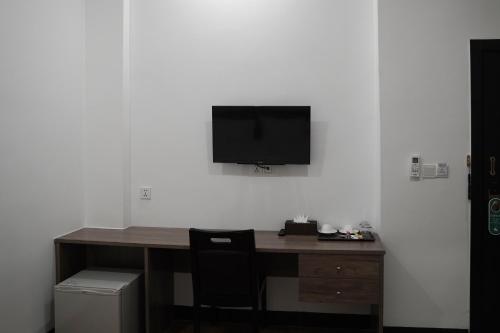 a desk with a television on a white wall at Apple Hotel Three - Phnom Penh in Phnom Penh