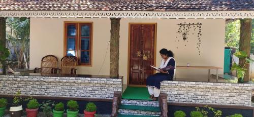 a woman sitting on the front of a house at Kailasam Home Stay in Munroe Island