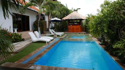 a swimming pool with chairs and a gazebo at Ocean Villa Dive Resort - Tulamben in Tulamben