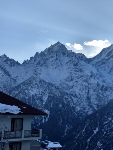 a snow covered mountain with a building in front of it at Hotel Rollingrang in Kalpa
