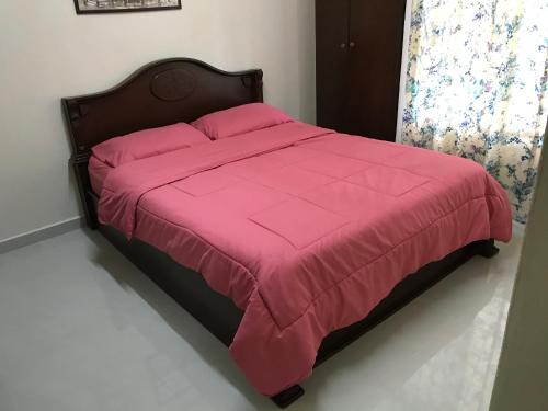 a bed with a pink comforter in a bedroom at Subang Ville Ehsan Apartment in Kampong Baharu Sungai Way