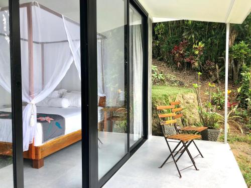 a bedroom with a bed and a chair on a balcony at Puncak Air Manis Residence in Padang