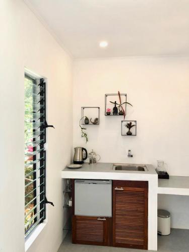 a white kitchen with a sink and a window at Puncak Air Manis Residence in Padang