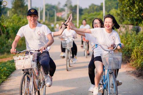 a group of people riding bikes down a street at Tomodachi Retreat - Làng Mít in Sơn Tây