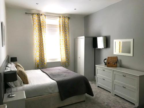 a bedroom with a bed and a window and a dresser at Seabreeze Restaurant With Rooms in Aberdyfi