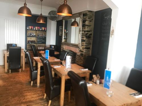 a dining room with wooden tables and black chairs at Seabreeze Restaurant With Rooms in Aberdyfi