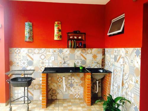 a kitchen with red walls and a counter with a sink at Aconchego e conforto em Joanópolis in Joanópolis