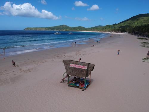 a lifeguard stand on a beach with people on it at Mad Monkey Hostel Nacpan Beach in El Nido