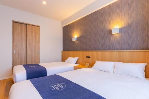 a hotel room with two beds and two lights on the wall at LAPIN MIHAMA Residence Hotel in Chatan