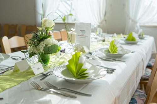 a table with white plates and flowers on it at Landgasthof Weberhans in Harburg