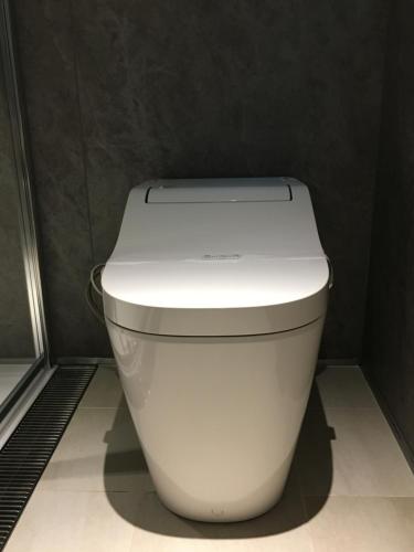 a white toilet in a bathroom with a black wall at Hotel 草石庵 in Osaka