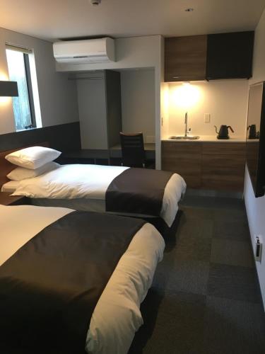 a hotel room with two beds and a kitchen at Hotel 草石庵 in Osaka