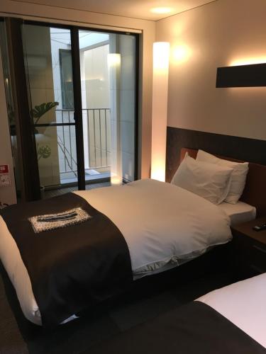 a bedroom with two beds and a large window at Hotel 草石庵 in Osaka