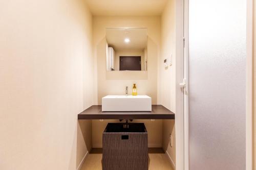 a bathroom with a sink and a mirror at LAPIN MIHAMA Residence Hotel in Chatan