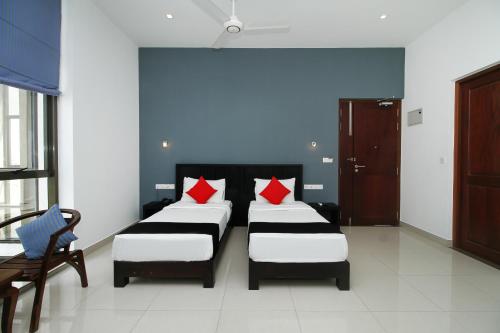 two beds with red pillows in a room at Golden Pier City Hotel in Colombo