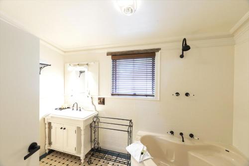 a white bathroom with a tub and a sink at Kaesler Cottages in Nuriootpa