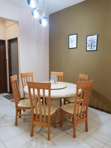 a dining room table with four chairs and a white table at Sandra Homestay in Tawau