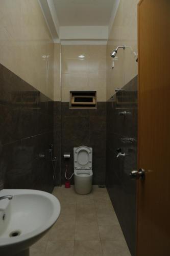 a bathroom with a white toilet and a sink at Birunthavanam in Vavuniya