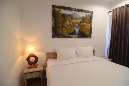 a bedroom with a bed and a painting on the wall at Sau Bali Beach House Canggu in Canggu