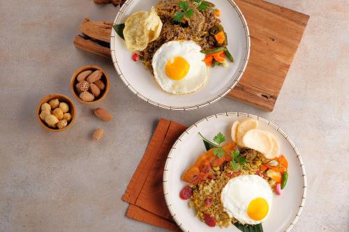 two plates of food with eggs on a table at Sau Bali Beach House Canggu in Canggu