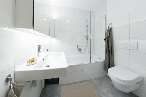 Baño blanco con lavabo y aseo en Landhaus Bergpanorama TOP 7, en Damüls