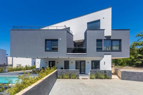 a large white house with a swimming pool at Luxury apartment NOA in Njivice