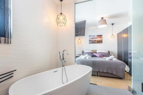 a bathroom with a tub and a bedroom with a bed at Luxury apartment NOA in Njivice