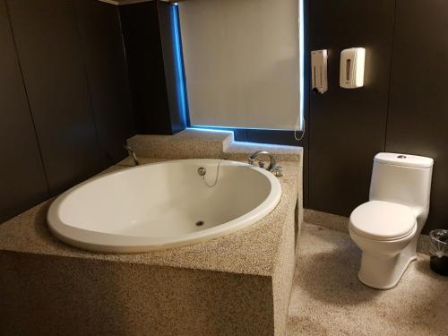a bathroom with a bath tub and a toilet at Walker Hotel - Sanchong in Taipei
