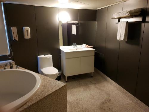 a bathroom with a sink and a toilet and a tub at Walker Hotel - Sanchong in Taipei
