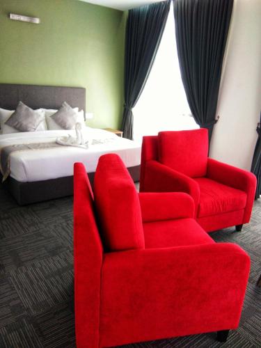 a bedroom with a red chair and a bed at We Hotel Langkawi in Kuah