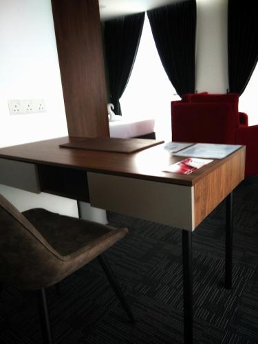 a desk in a room with a chair and a table at We Hotel Langkawi in Kuah