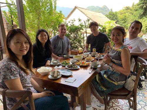 a group of people sitting around a table eating food at Mai Chau Rustic Home in Mai Chau