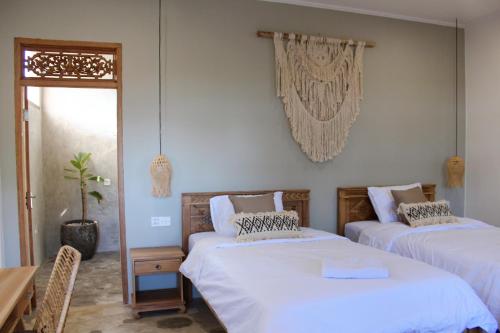 a bedroom with two beds and a table and a window at The Inn Possible in Uluwatu