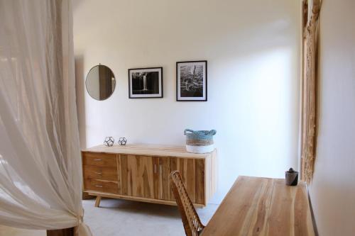 a dining room with a wooden table and a mirror at The Inn Possible in Uluwatu