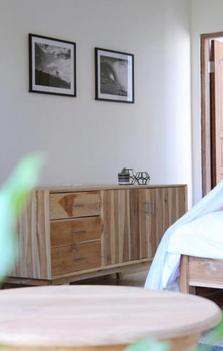 a room with a wooden dresser with two pictures on the wall at The Inn Possible in Uluwatu