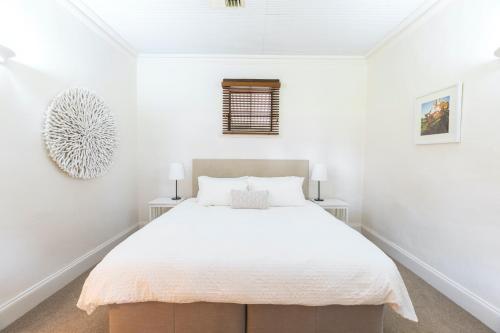 a white bed sitting in a bedroom next to a wall at Kaesler Cottages in Nuriootpa