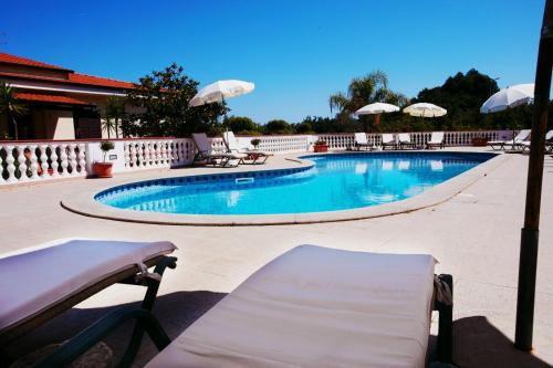 a swimming pool with lounge chairs and umbrellas at Fonte Di Bagnaria in Santa Domenica