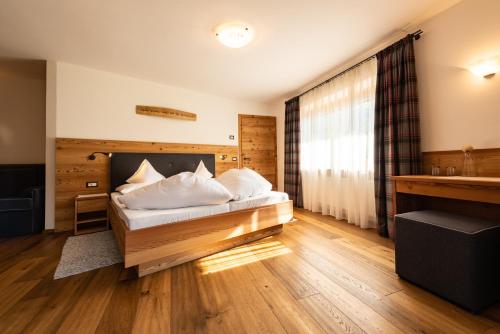 Habitación de hotel con cama y ventana en Garni Hotel Geier, en Santa Cristina Valgardena