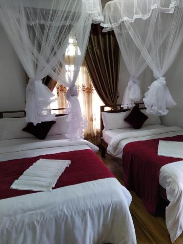 two beds in a room with white curtains at RIO Homestay in Haputale